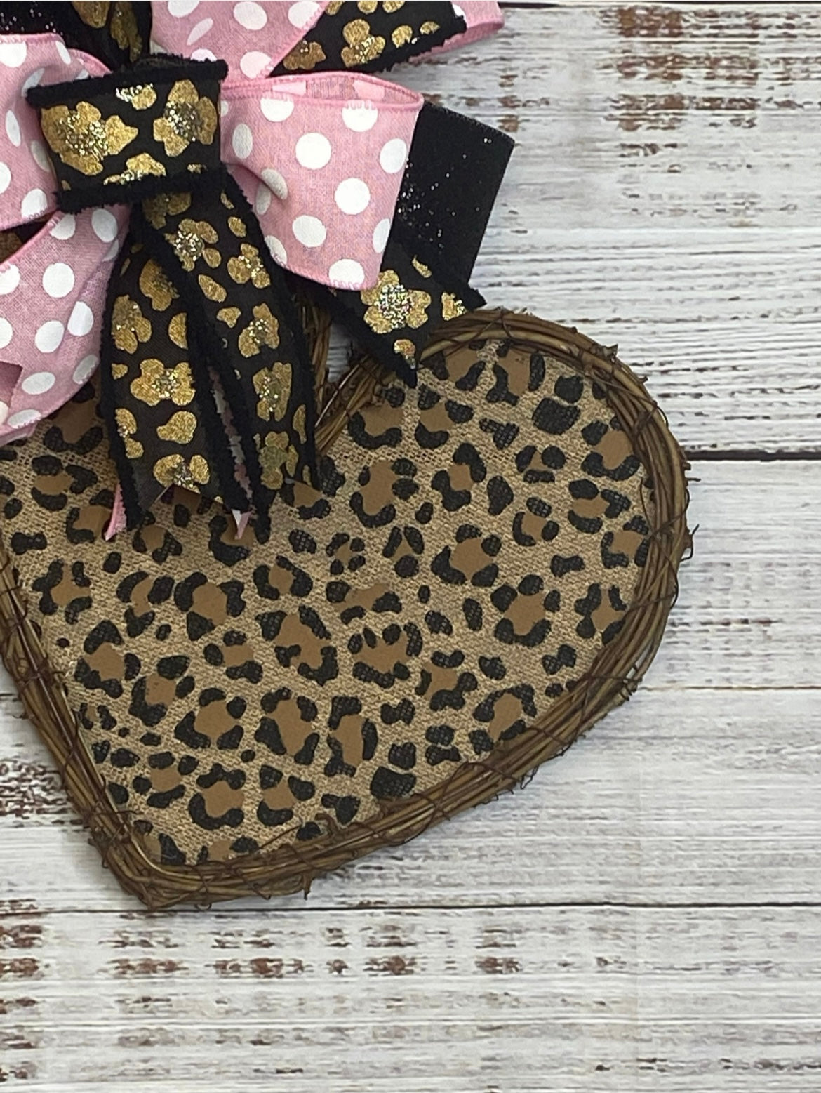 Heart-shaped jute mat with leopard print and decorative bows on a wooden surface