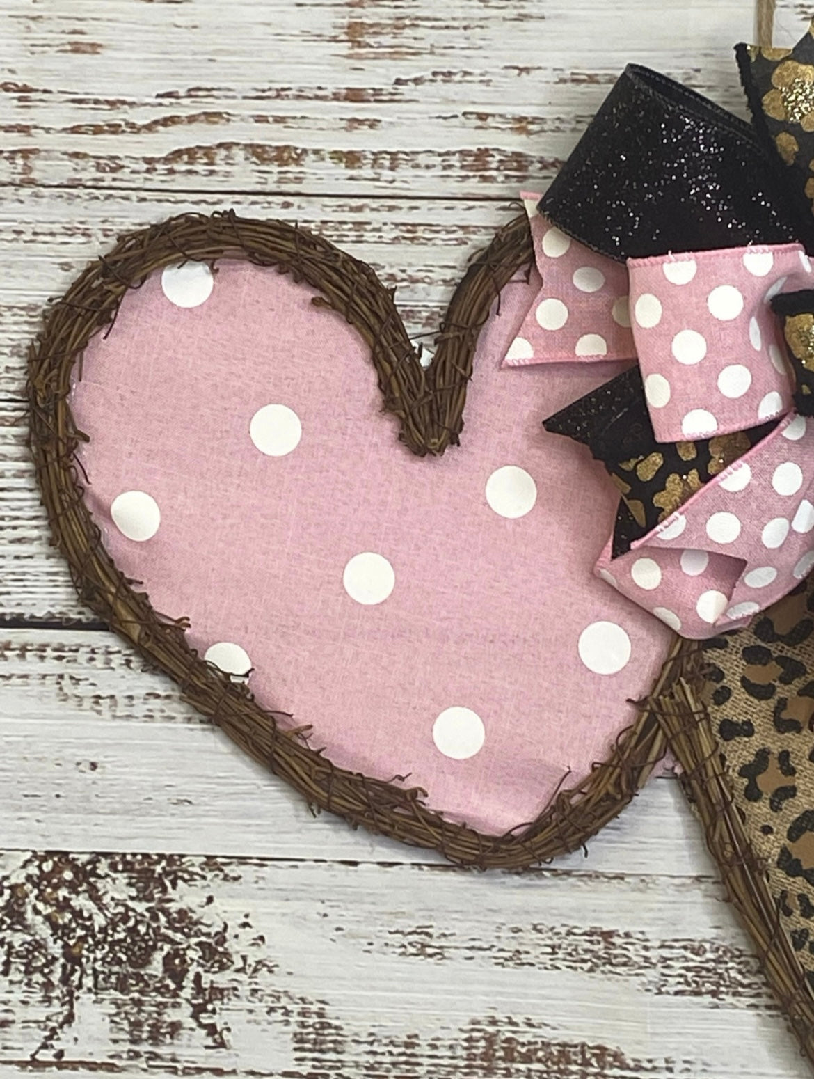 Heart-shaped pink fabric with white polka dots on a rustic wooden surface