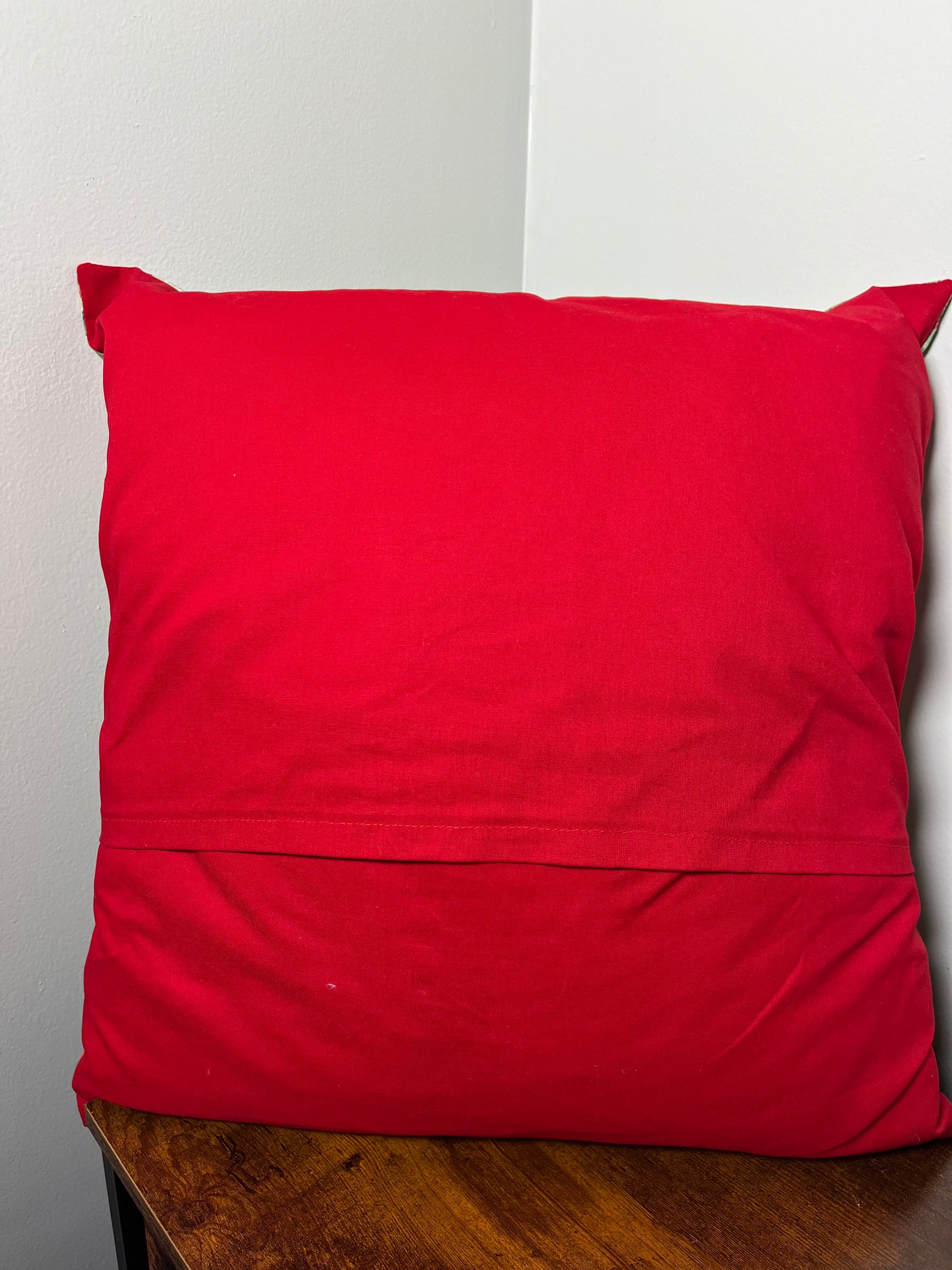 Red backing on Christmas Cardinal pillow on a wooden surface with a white background