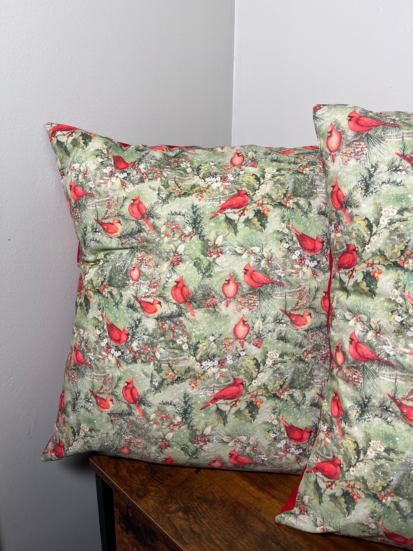 Christmas themed pillow with red cardinal design on a plain background