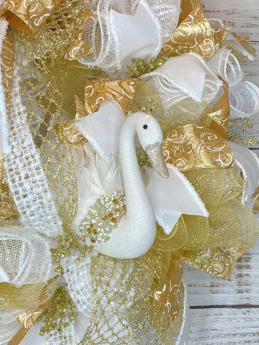 Decorative swan ornament with gold and white ribbons on a wreath  on a wooden background
