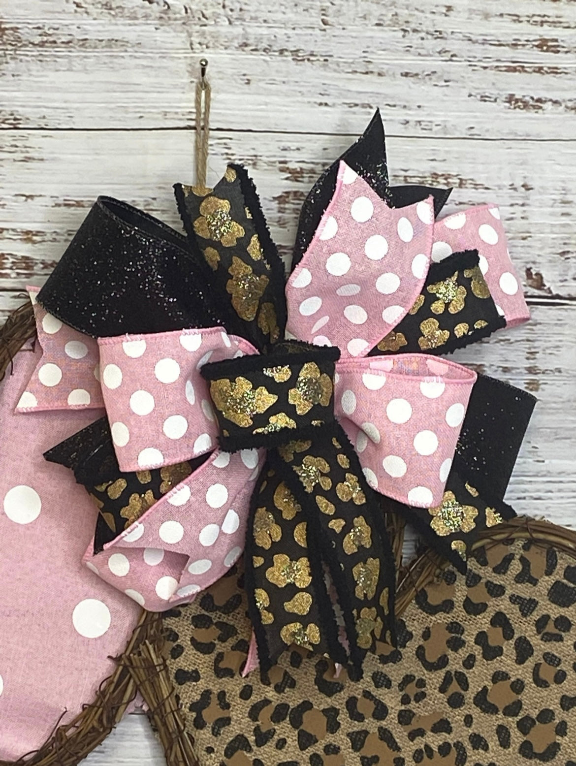 Decorative bow with pink, black, and gold patterns on a wooden background