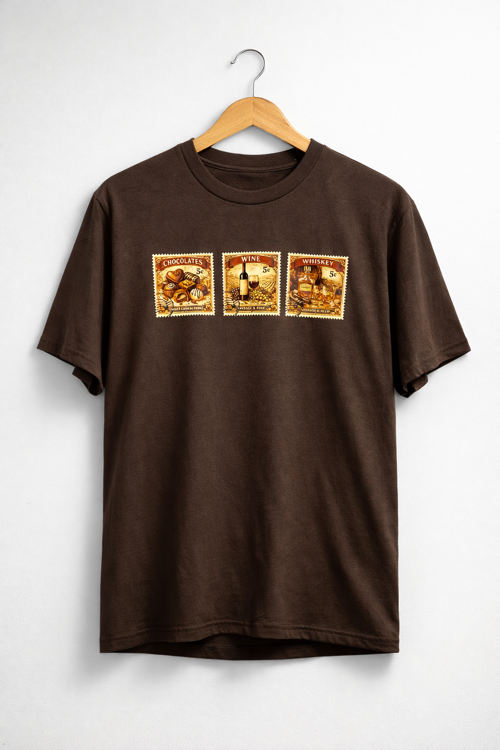 Brown short sleeve shirt with three vintage stamp theme graphics on front chest representing whiskey, wine and chocolate on a hanger