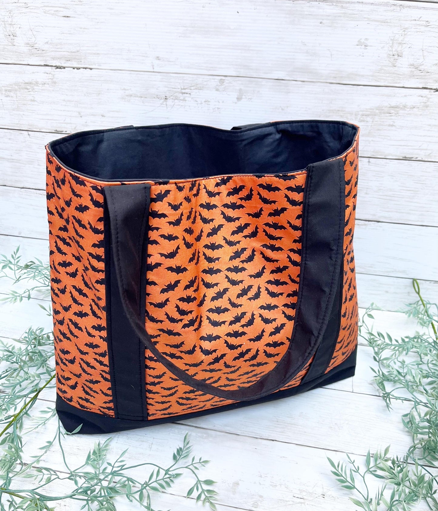 Tote bag with orange and black bat pattern on a wooden surface