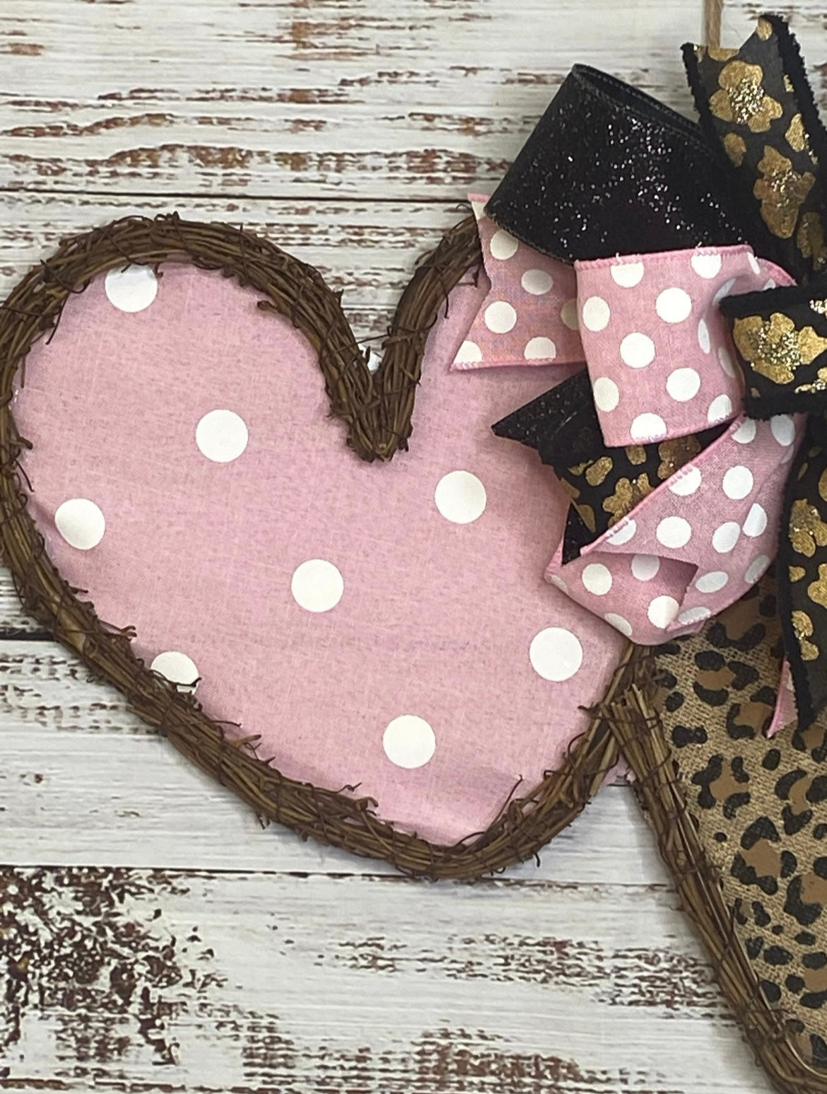 Heart-shaped pink fabric with white polka dots on a wooden surface
