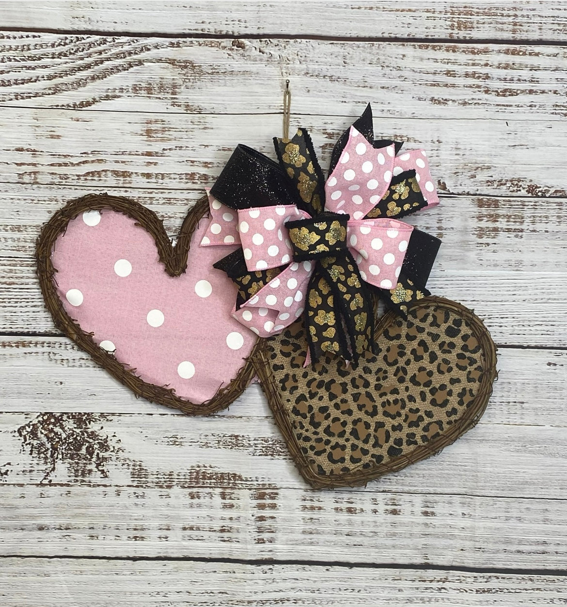 Heart-shaped decorative item with pink polka dot and leopard print design on a wooden surface
