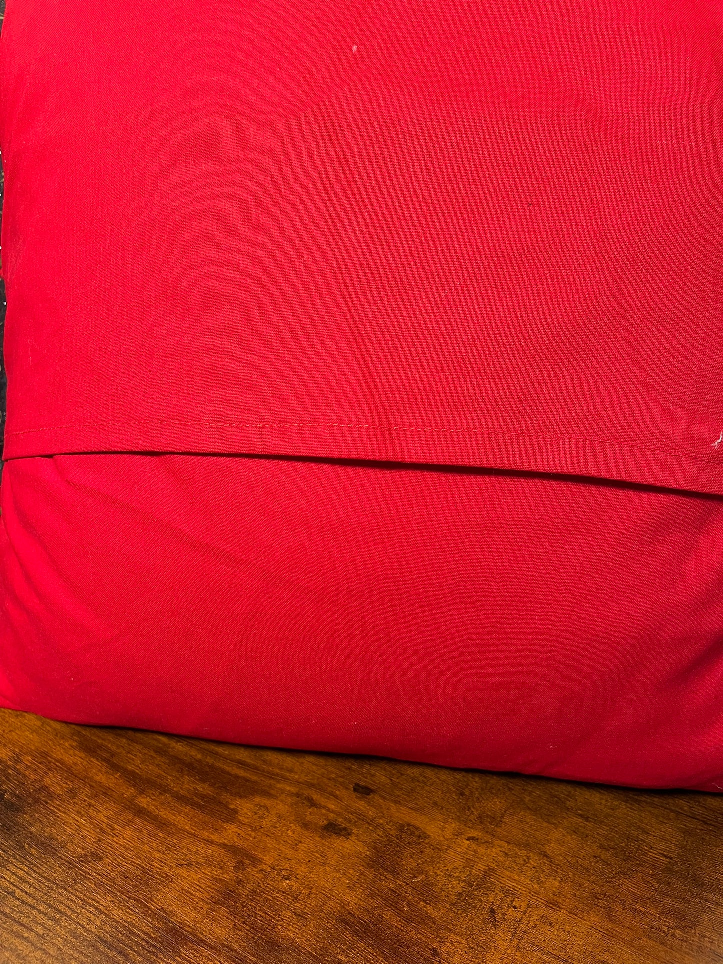 close up of red fabric on back of holly pillow on a wooden surface