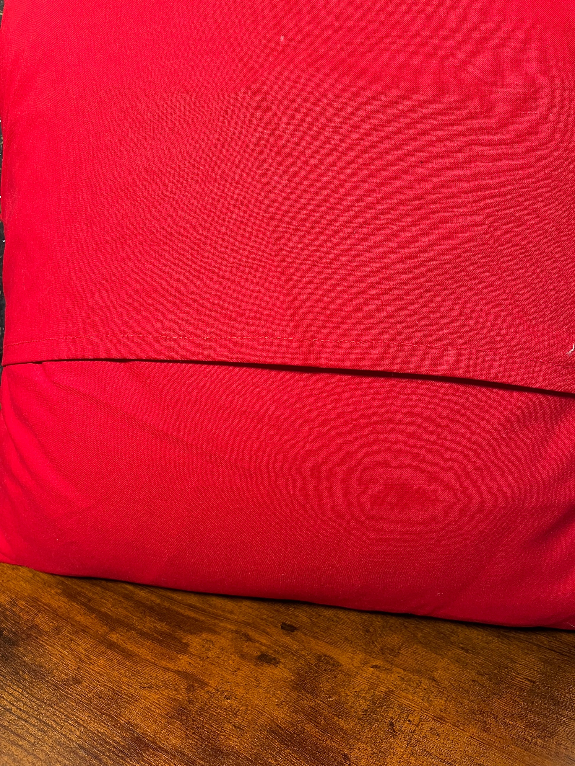 close up of red fabric on back of holly pillow on a wooden surface