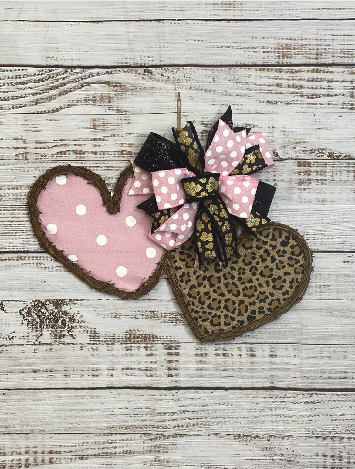 Heart-shaped pink and leopard print fabric with a decorative bow on a wooden surface