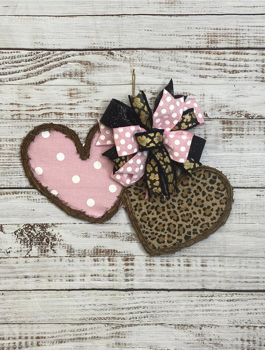Heart-shaped pink and leopard print fabric with a decorative bow on a wooden surface