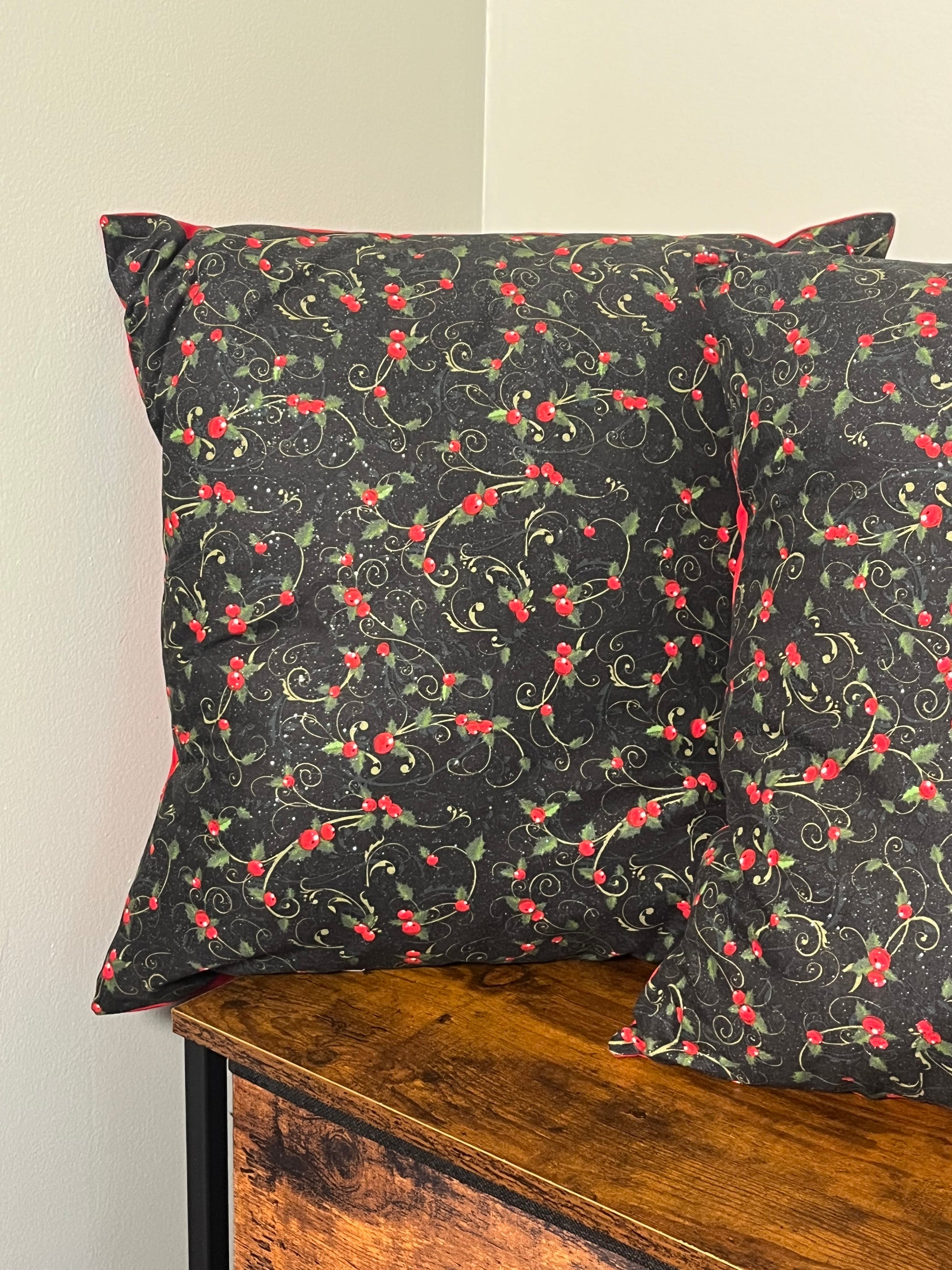 Holly berry Christmas pillow with black background displayed on wooden dresser