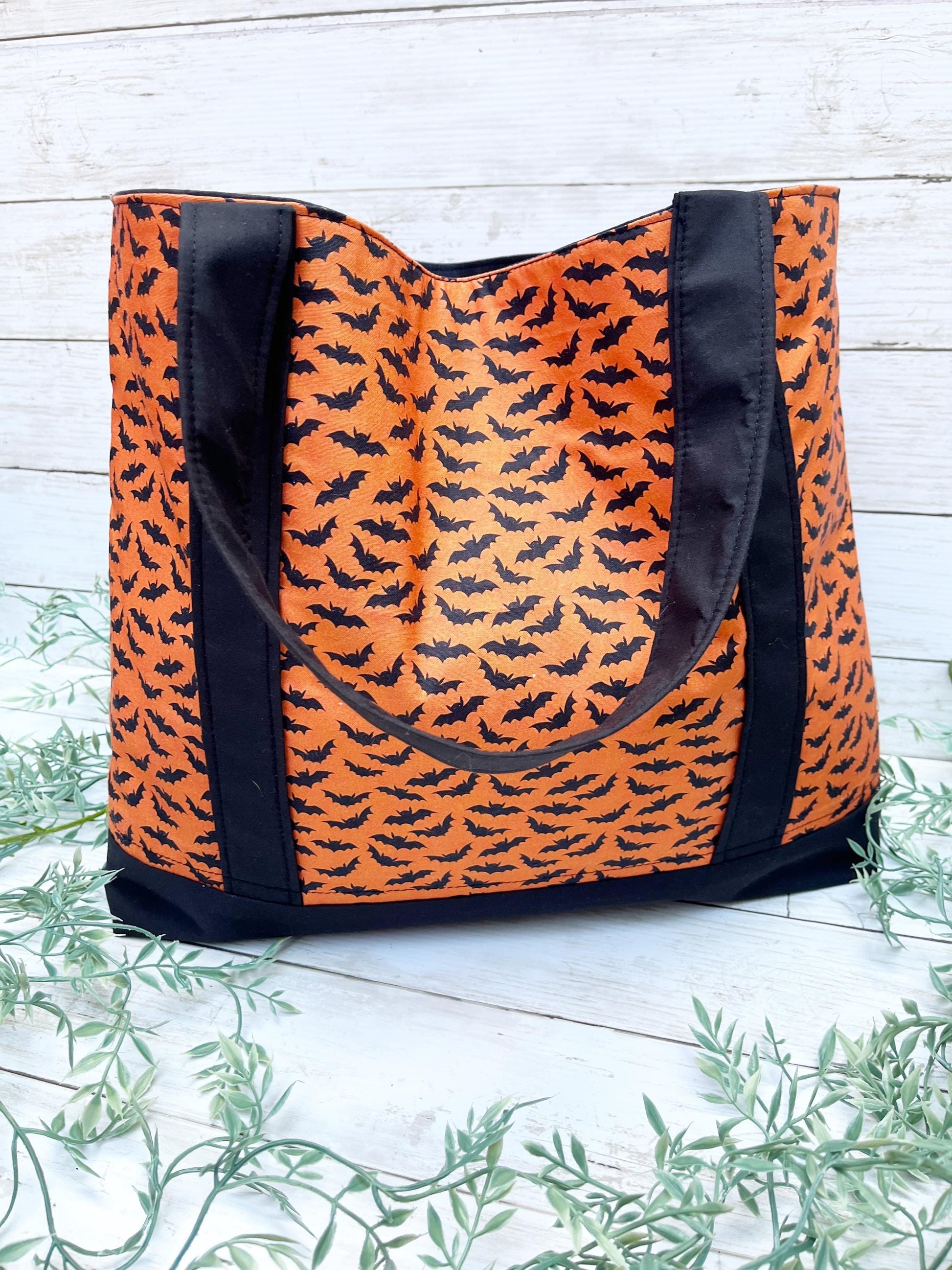 Orange tote bag with black bat pattern on a light wooden background