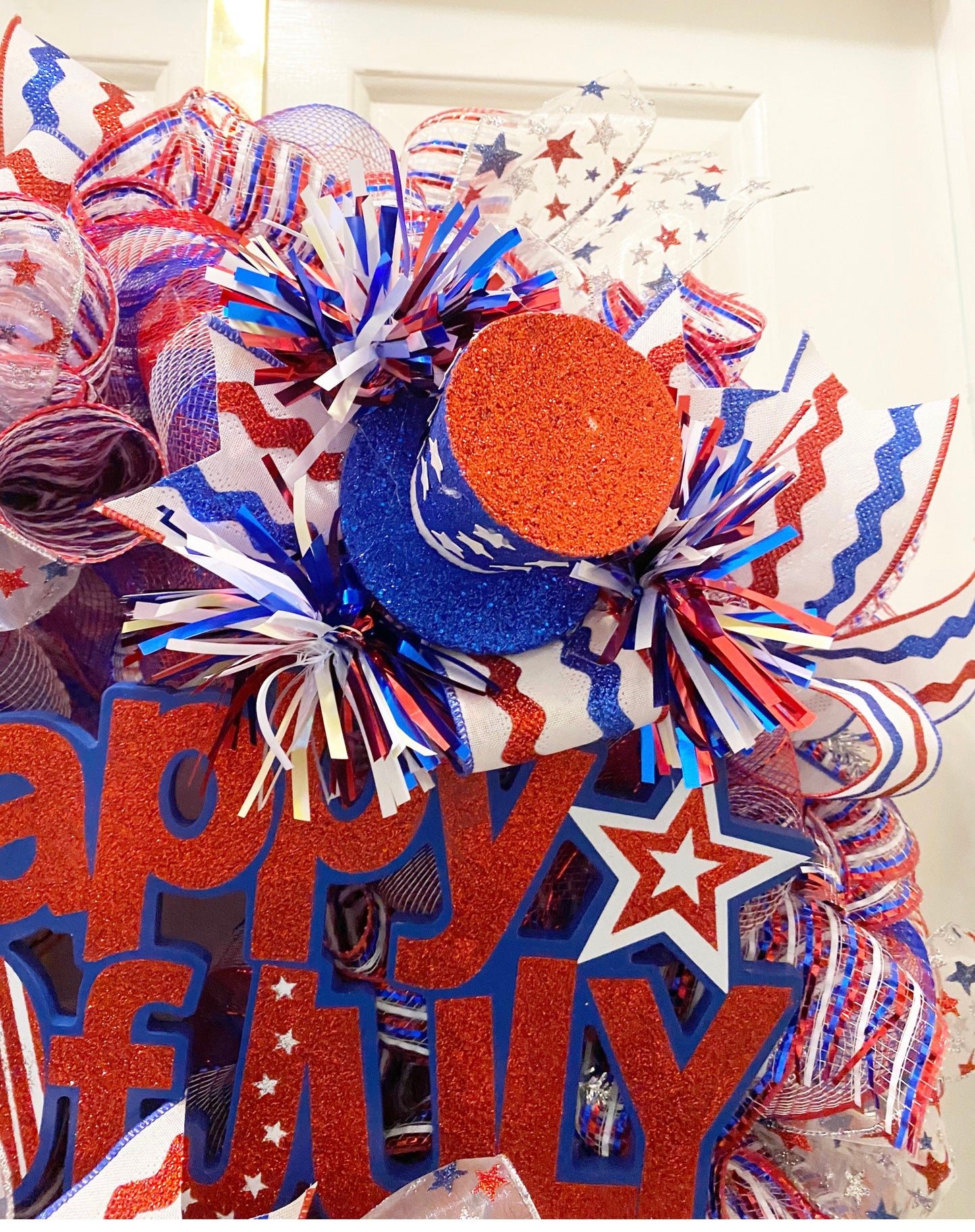 Decorative wreath with red, white, and blue colors featuring 'Happy July' text.
